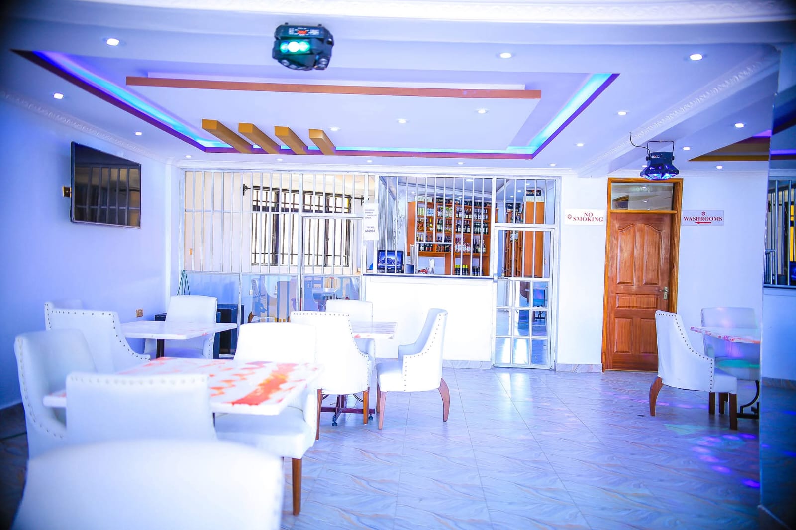 Emerald Lounge bar area with blue LED lighting, ornate terracotta ceiling, and well-stocked bar at Kitui Premier Resort